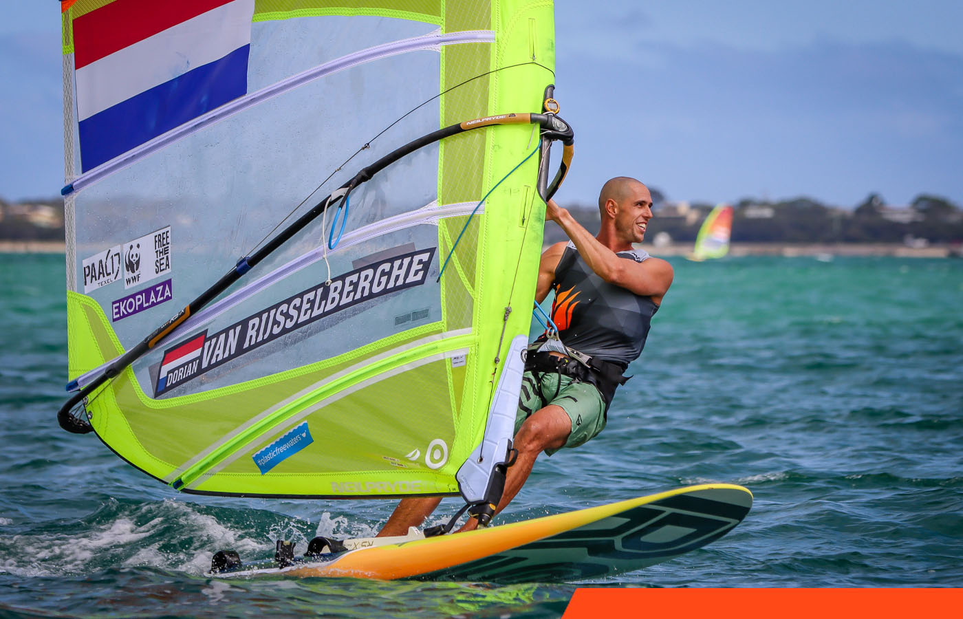 Dorian van Rijsselberghe windsurfend met een geel zeil met zijn naam erop